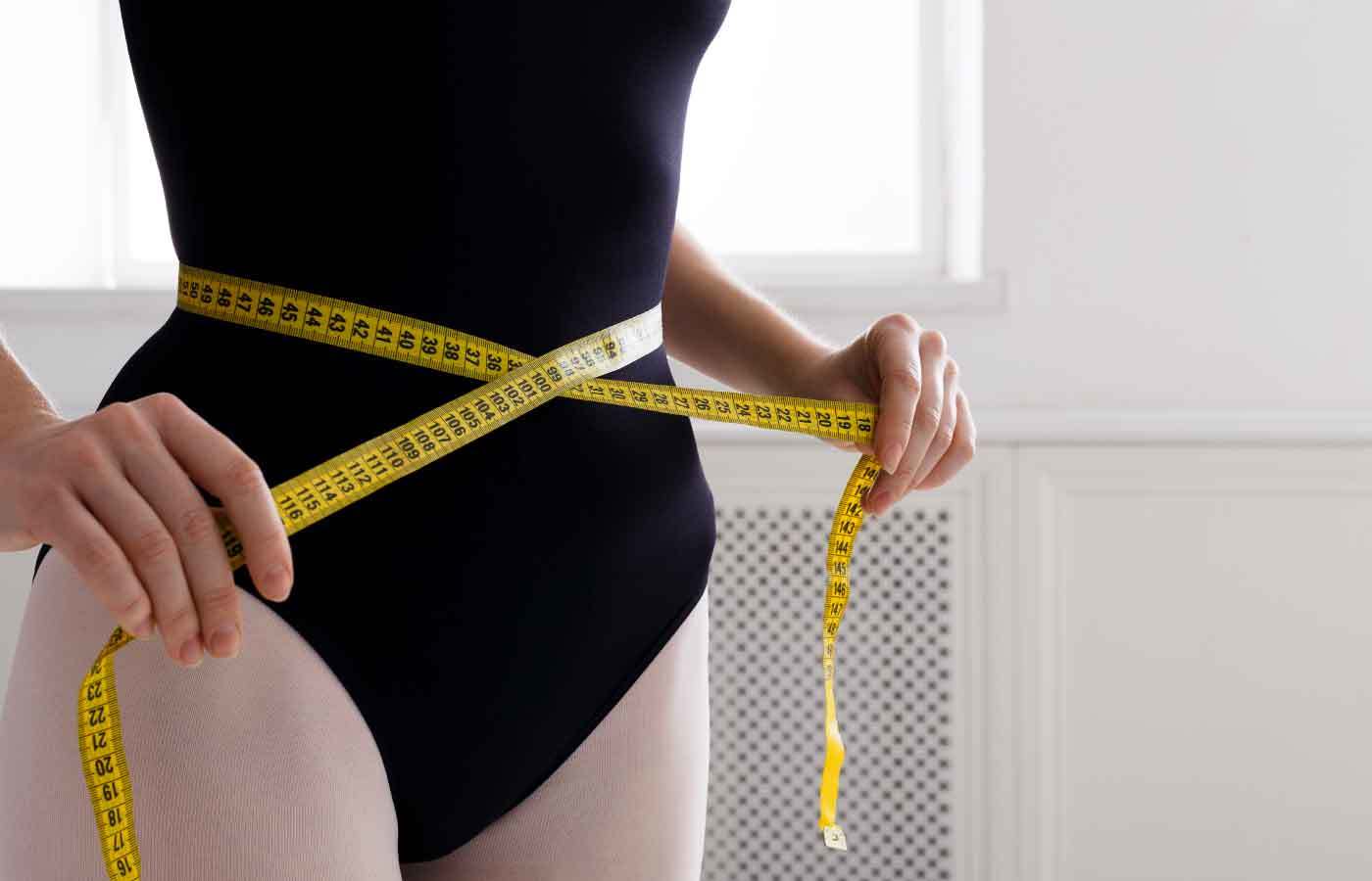 a woman measuring her waist after trying a weight loss progra