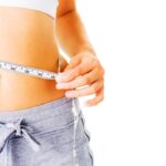 a woman measuring her waist after undergoing a phycian prescribed weight loss program