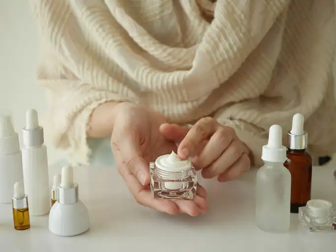 Woman's hands holding skincare cream jar.