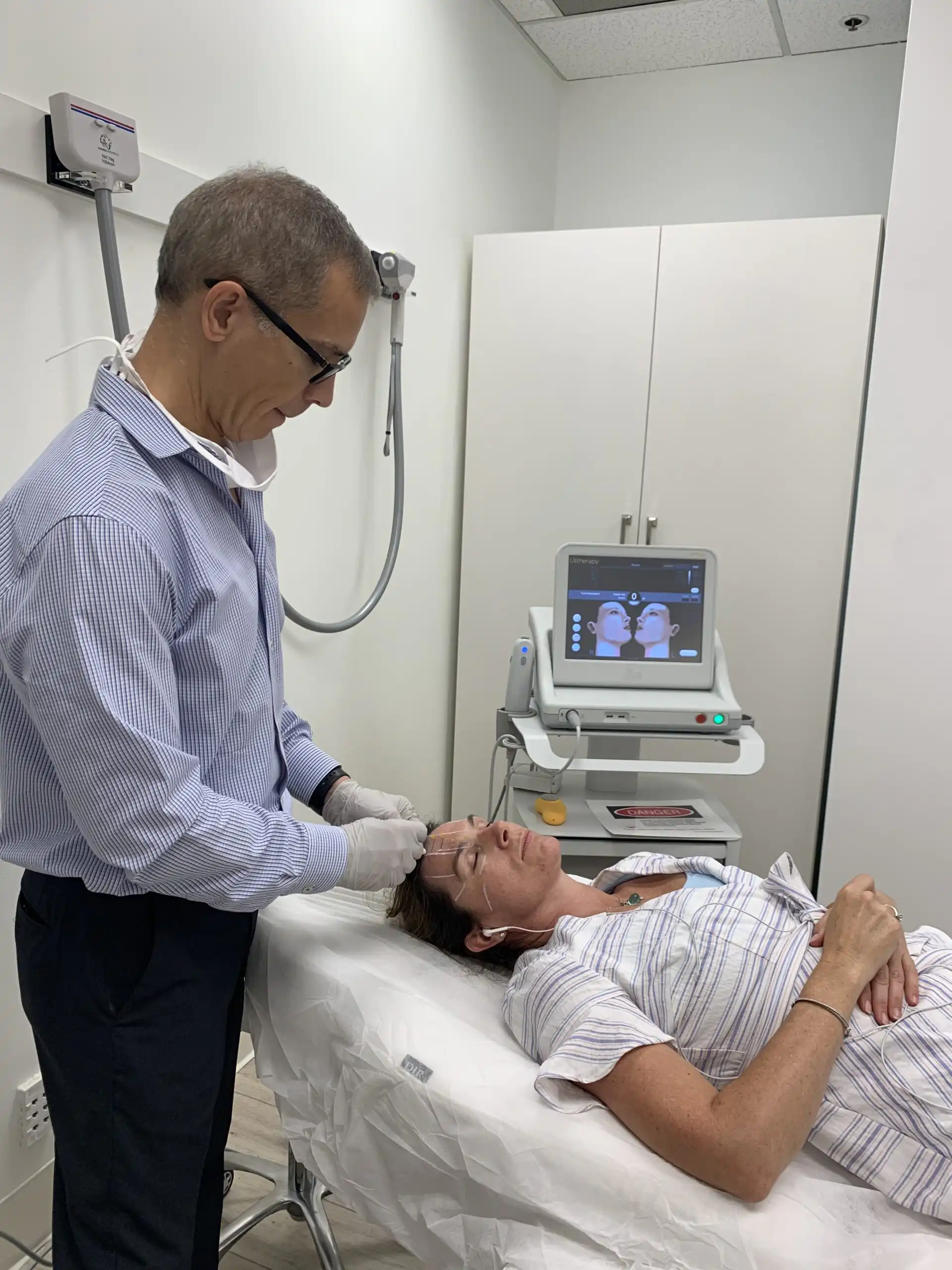 Doctor performing Ultherapy facial treatment.