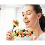 A smiling woman enjoying a bowl of fresh salad with leafy greens, tomatoes, and cucumbers, symbolizing a healthy lifestyle and nutritious eating showing healthy foods for weight loss